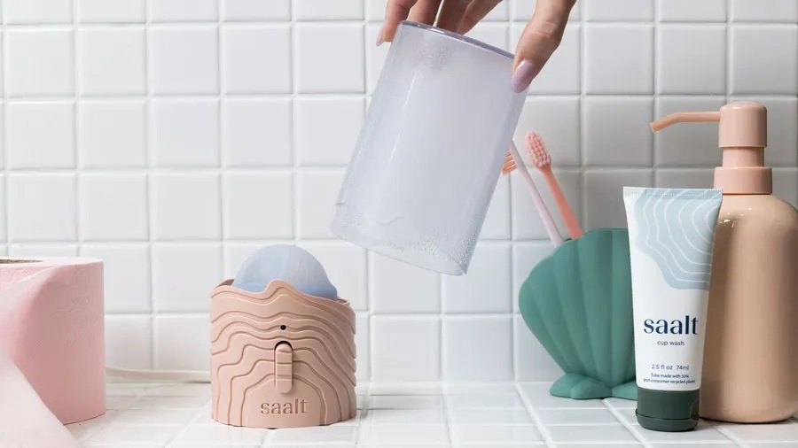Hand placing clear lid over Saalt Menstrual Cup Steamer on tiled counter
