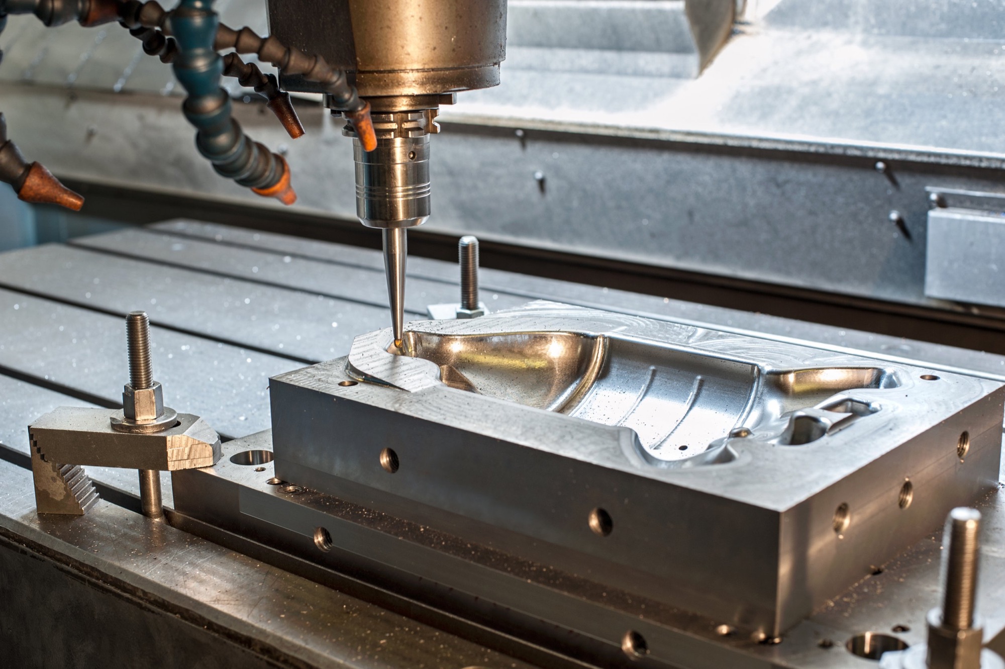 A CNC machine drilling into a metal mold or component in a manufacturing setting.