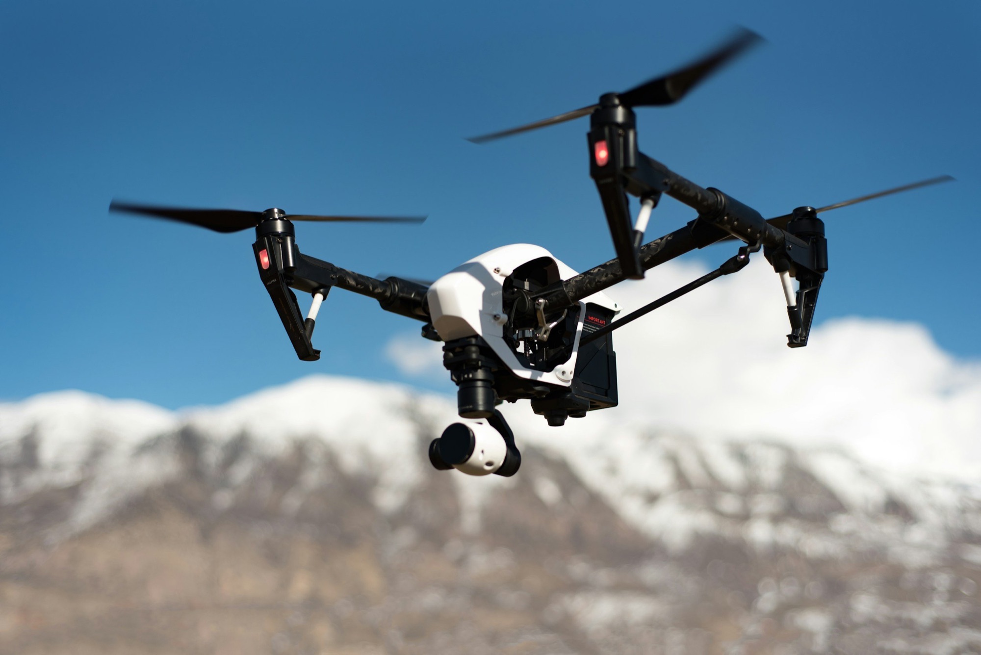 A drone flying with snow-covered mountains in the background.