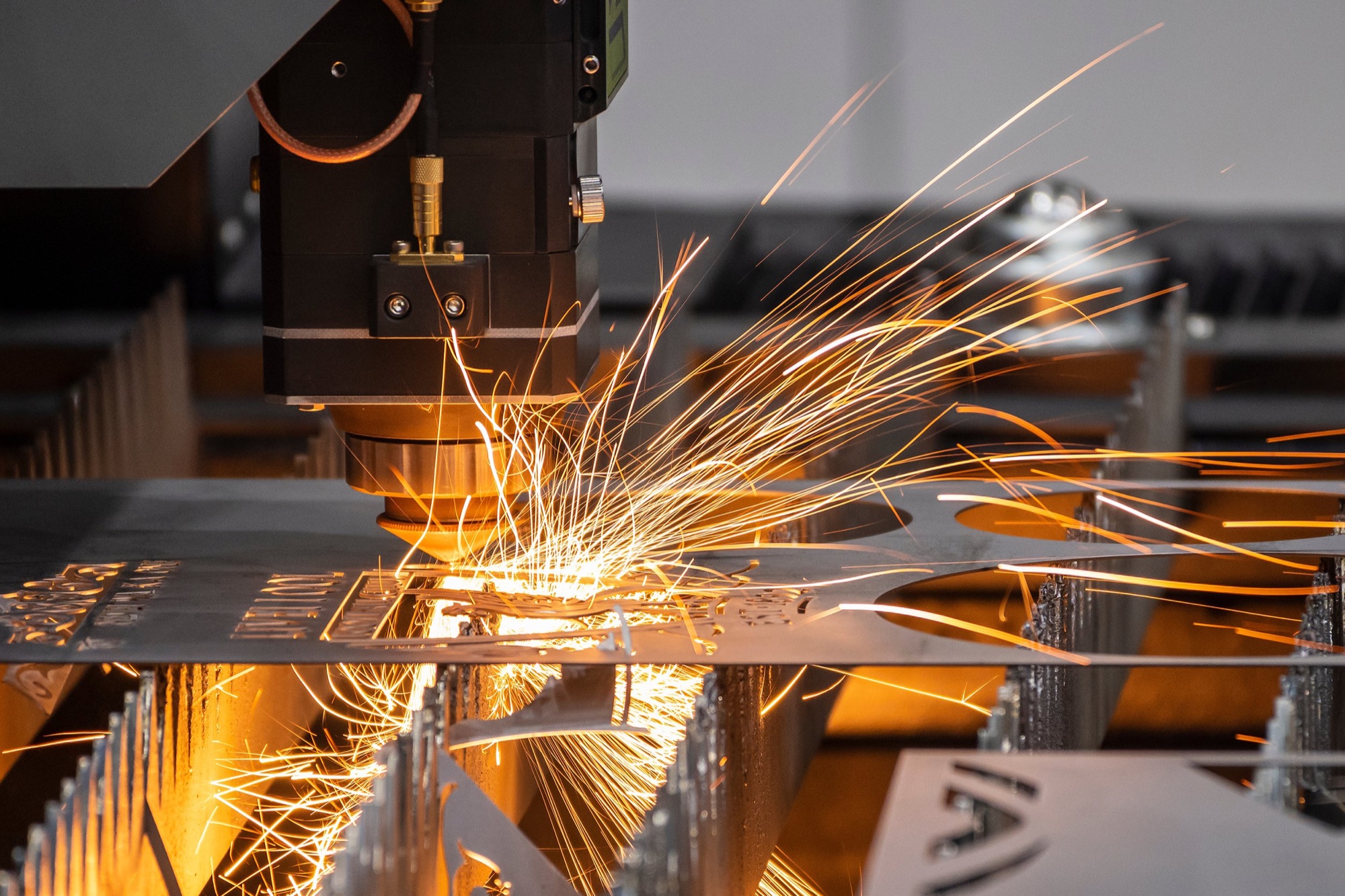 A laser cutter or welder generating sparks as it cuts or welds metal sheets in an industrial setting.