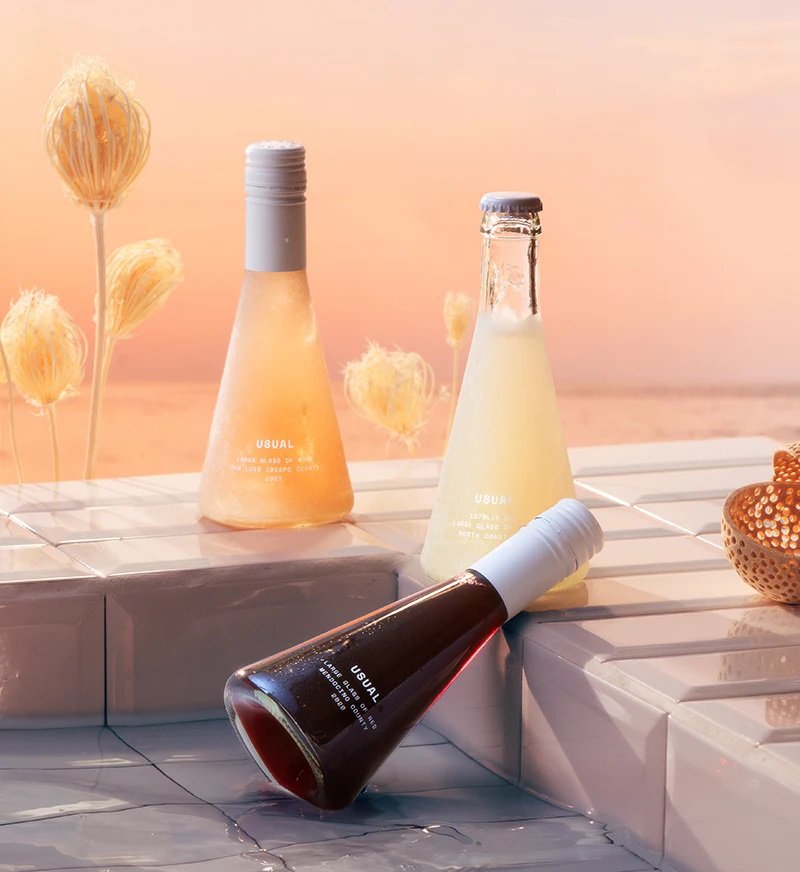 Usual single glass wine bottles outdoors on a sunny day with a peach-toned backdrop