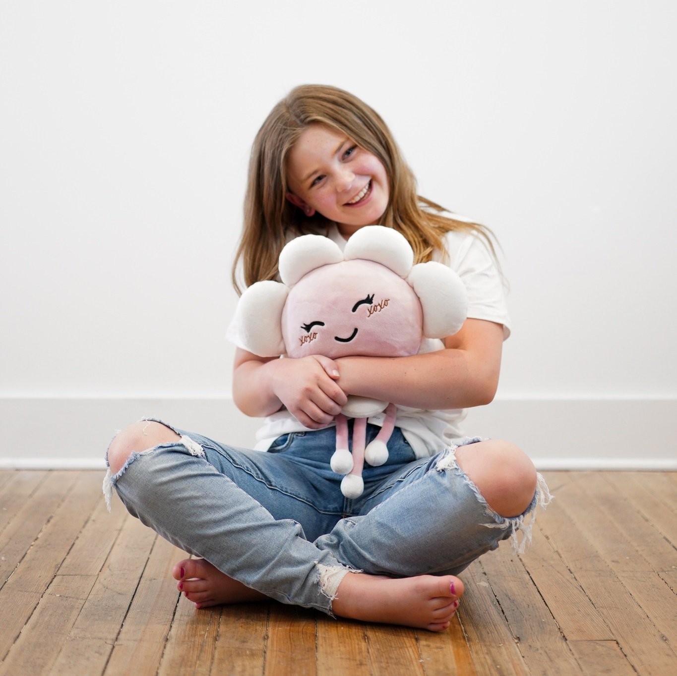 Adult holding a Kaia Comfort plush flower-shaped heated stuffed animal while sitting for relaxation.