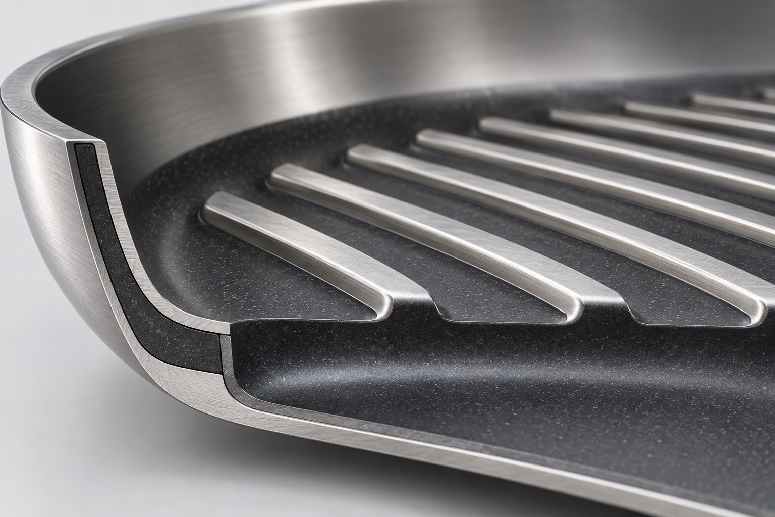Close conceptual view of raised steel ribs above a recessed nonstick cooking surface.